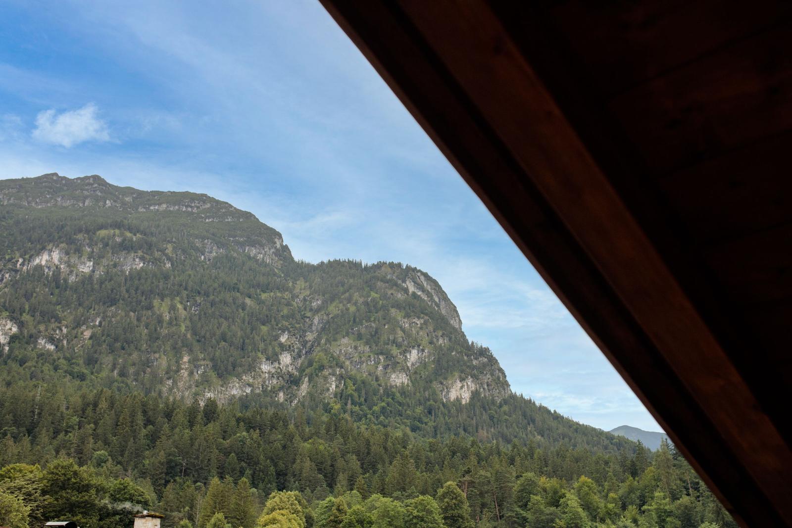 Blick auf bewaldete Berge von einem Holzdach aus.