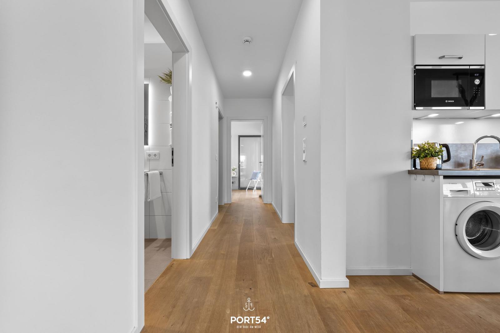 Flur mit Holzboden, Küche mit Waschmaschine und Mikrowelle