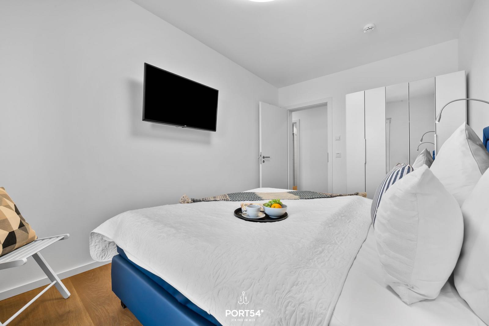 Schlafzimmer mit Bett, Fernseher und Kleiderschrank.