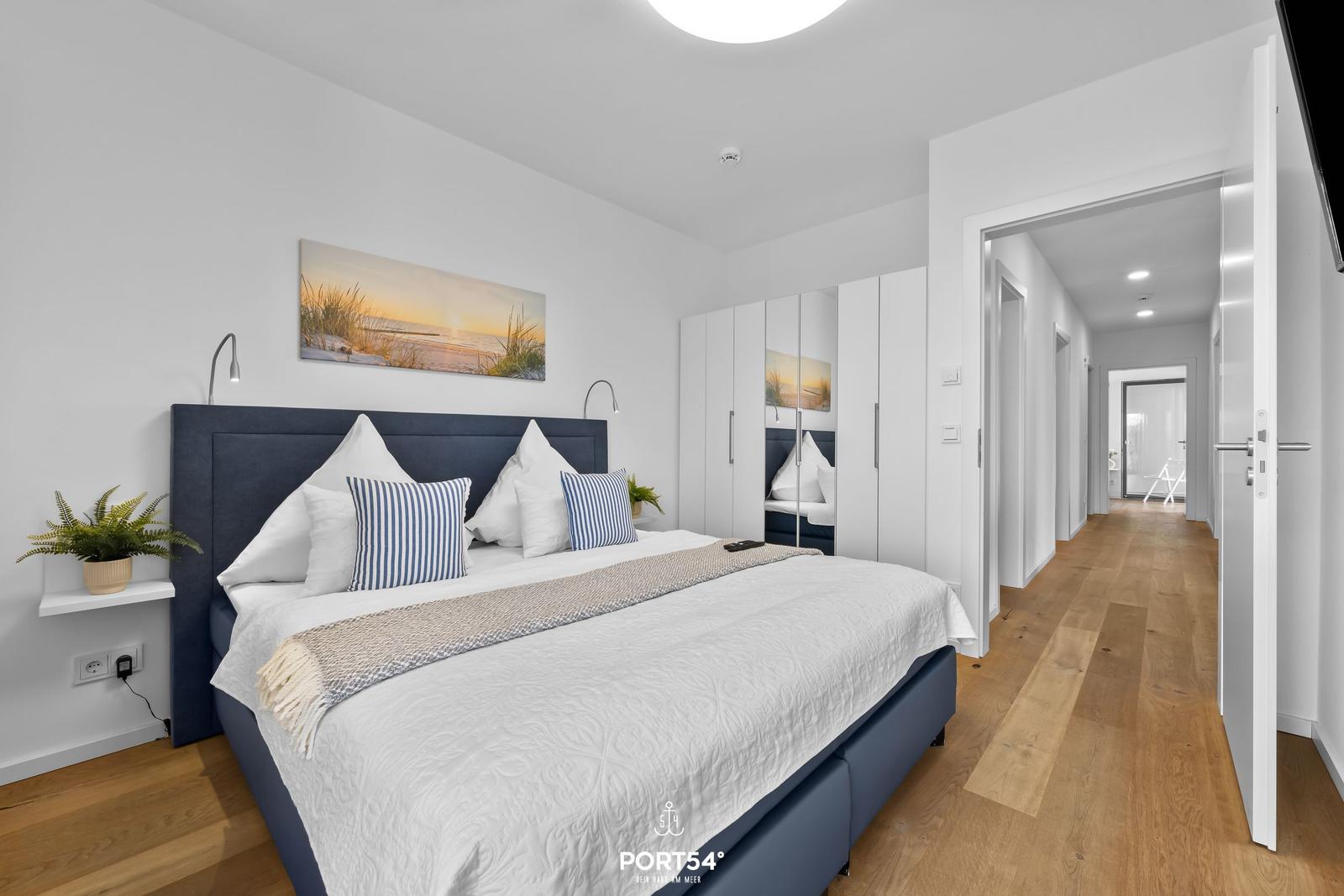 Schlafzimmer mit Bett, Kleiderschrank und Flur. Wandbild und Pflanzen.