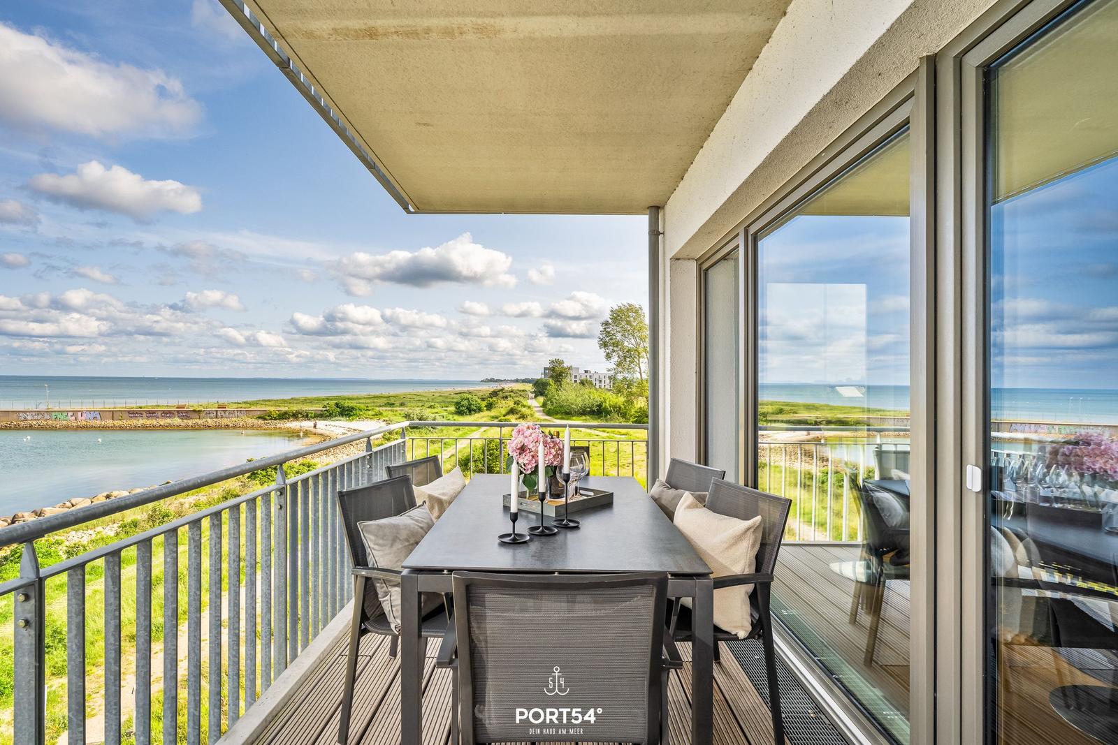 Terrasse mit Sitzgruppe und Meerblick. Tisch mit Blumen und Kerzen.