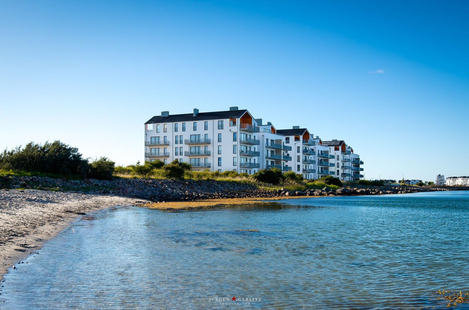 Moderne Wohnanlage am Strand mit Balkonen und klarem Himmel.