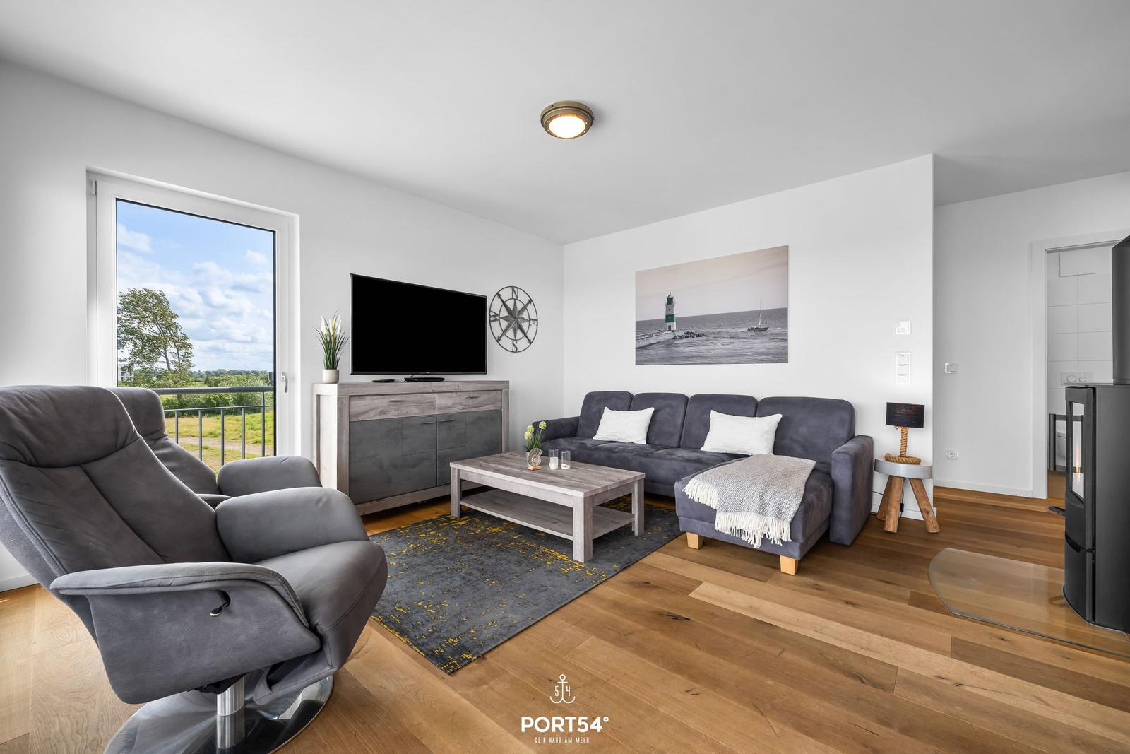 Wohnzimmer mit Sofa, Fernseher und Blick auf Balkon.