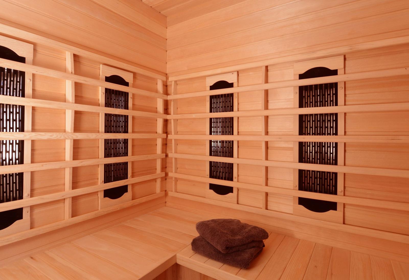Sauna mit Holzbank und dunklen Handtüchern an der Wand.