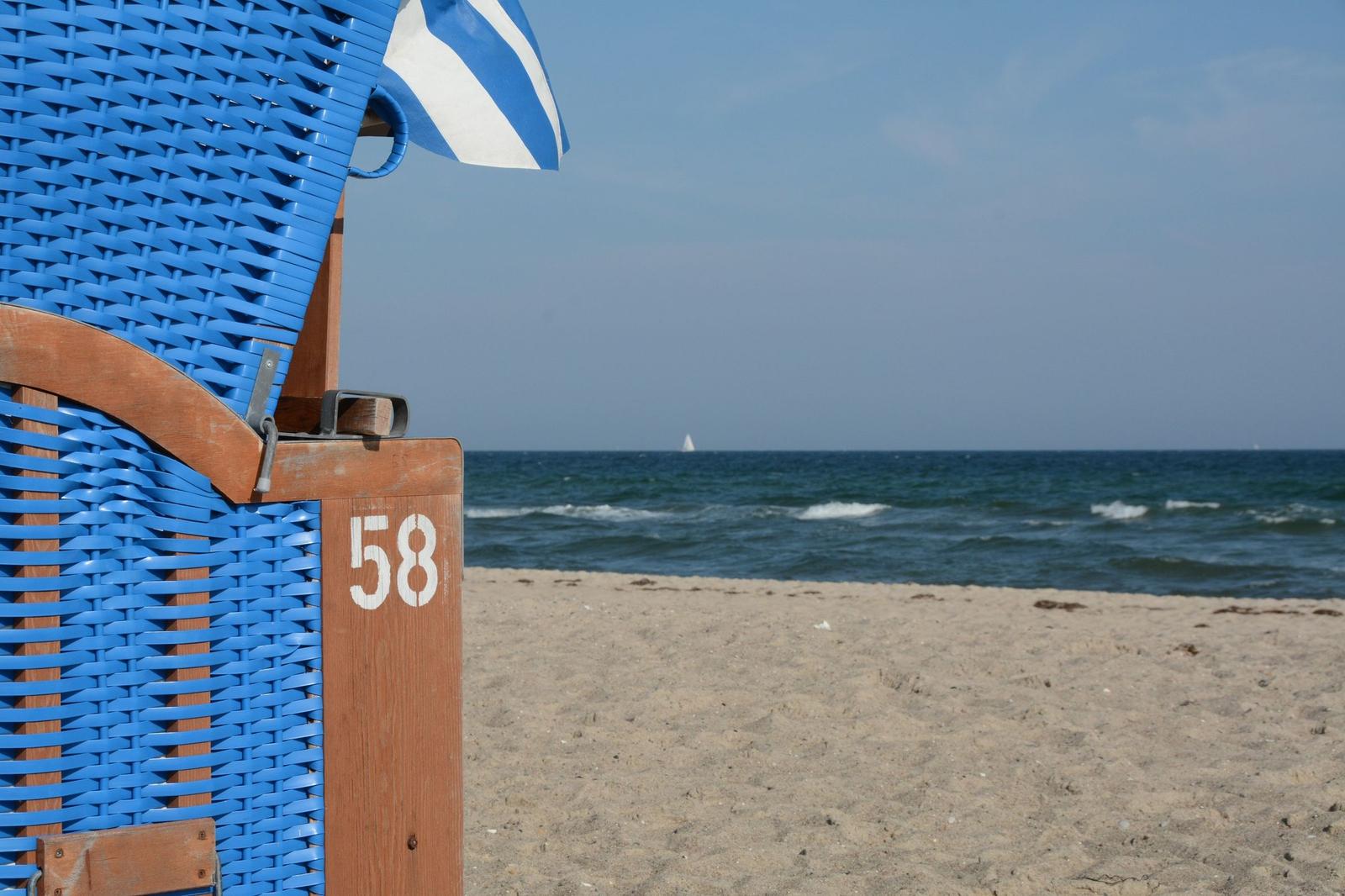 Blauer Strandkorb mit Nummer 58 und griechischer Flagge am Strand.
