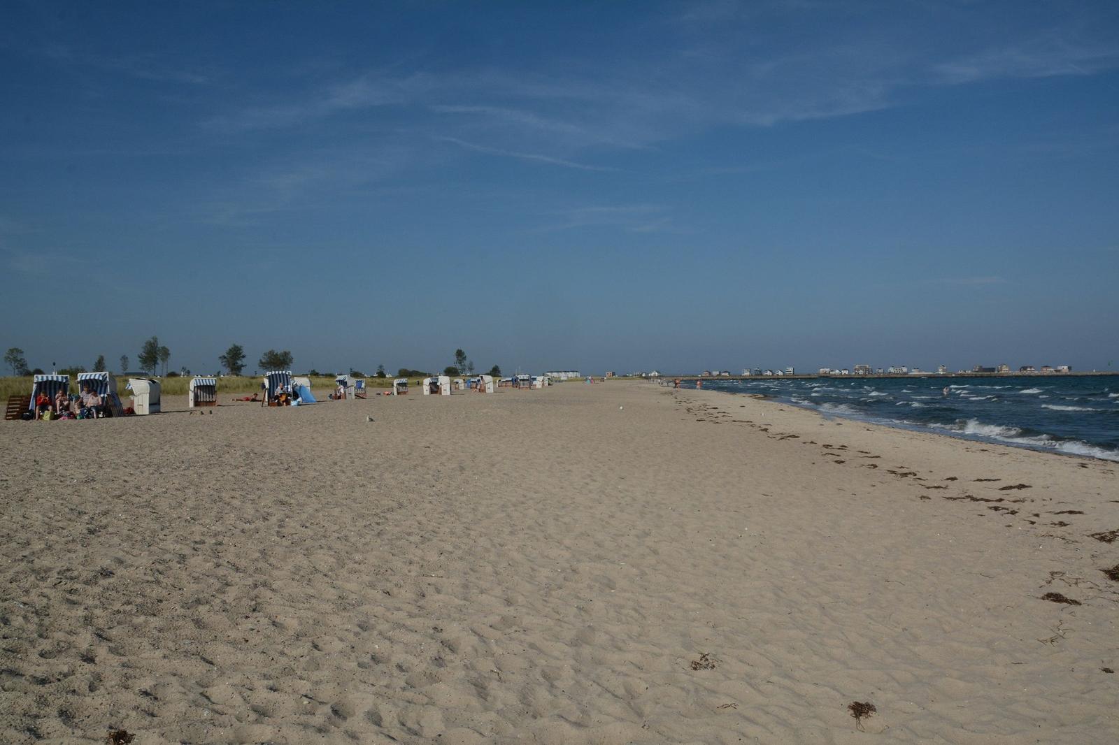 Strand mit Strandkörben und Meer unter blauem Himmel