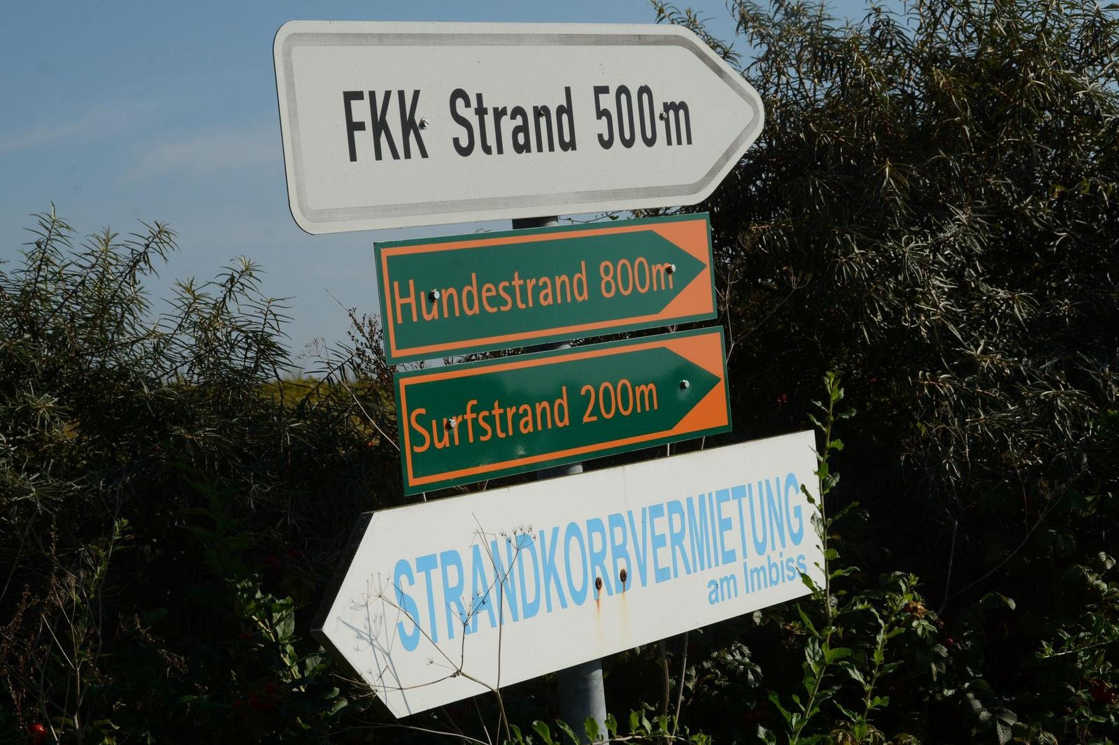 Schilder weisen auf FKK-Strand, Hundestrand und Surfstrand hin.