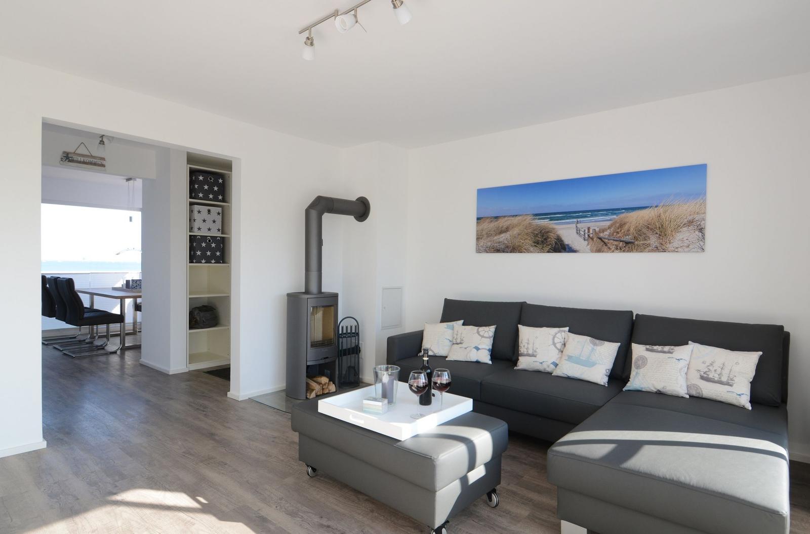 Wohnzimmer mit Sofa, Kamin und Küchenbereich im Hintergrund.