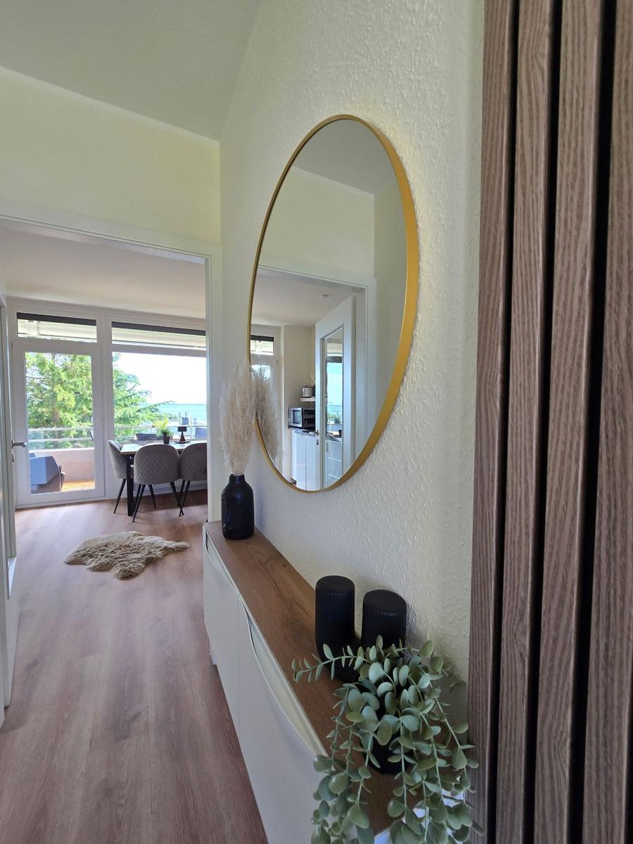 Eingangsbereich mit Spiegel, Pflanzen und Blick auf Terrasse mit Meerblick.