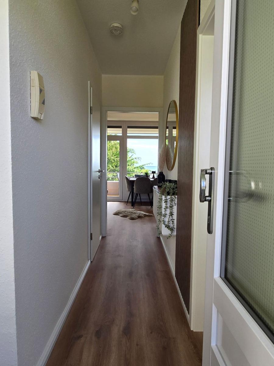 Flur mit Holzboden, Blick auf Essbereich und Balkon mit Meerblick.