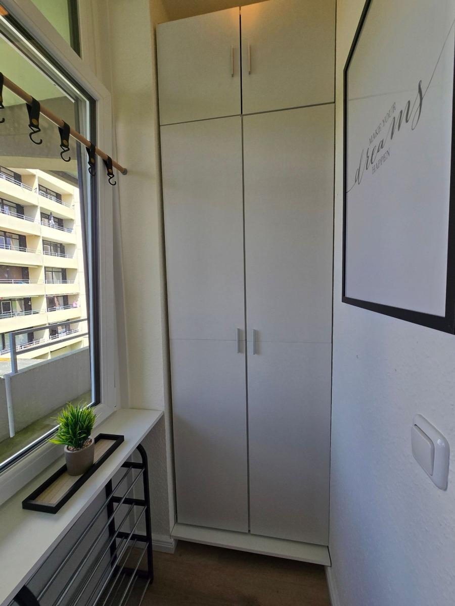 Schlafzimmer mit Kleiderschrank, Fenster und Bild an der Wand.