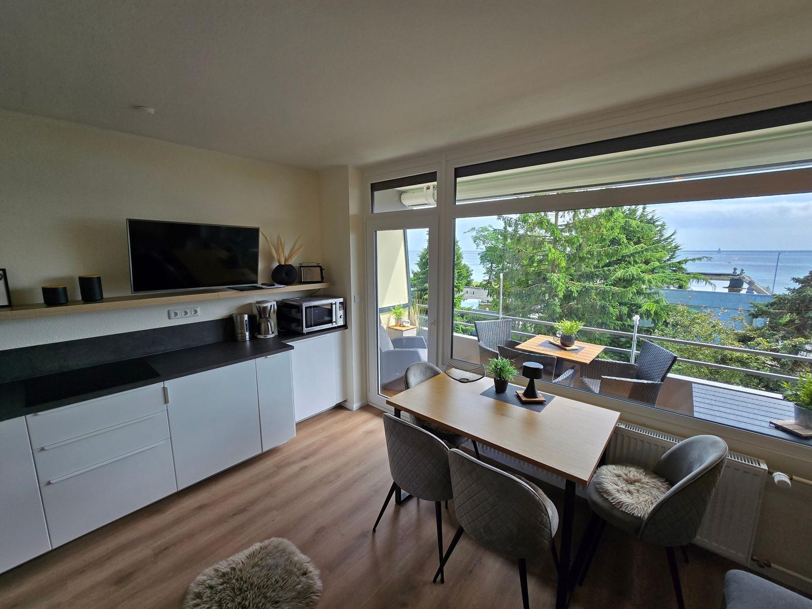 Wohnküche mit Essbereich und Balkonblick aufs Meer.