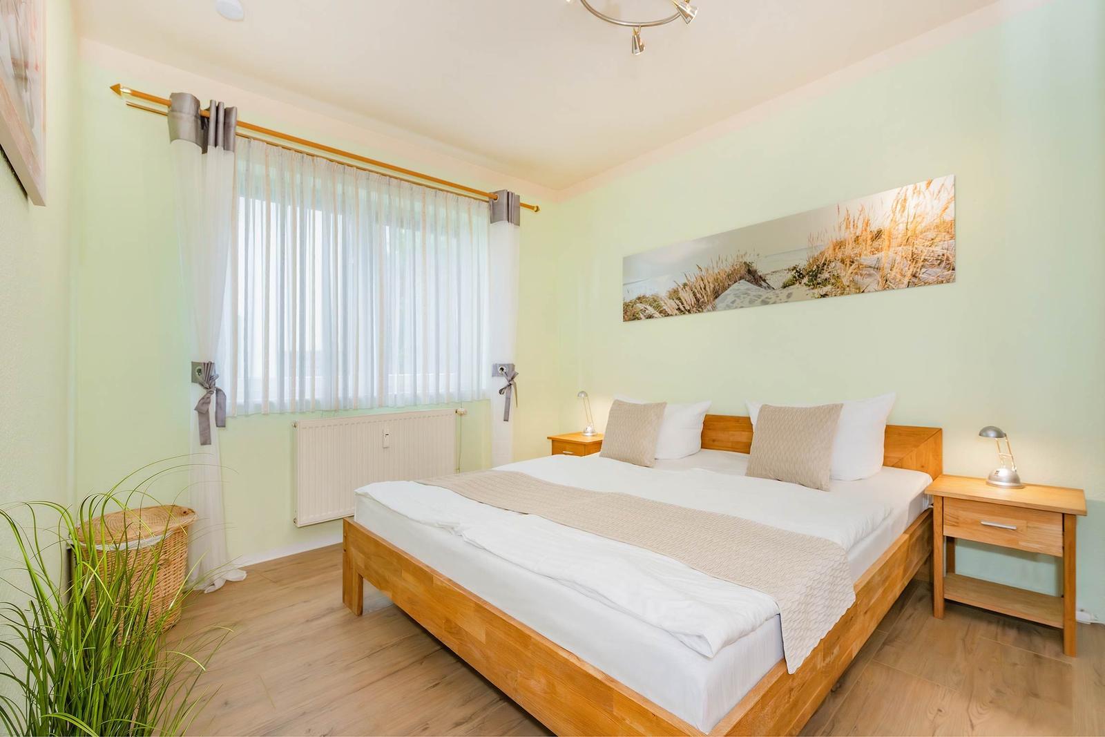 Ein Schlafzimmer mit Doppelbett, zwei Nachttischen und einem Fenster mit Vorhängen.