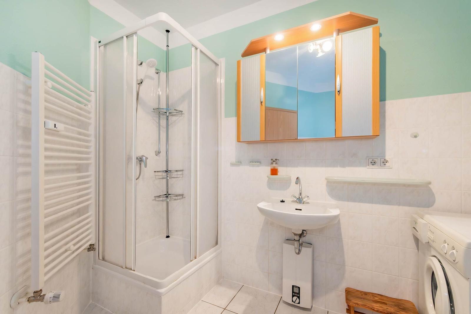 Badezimmer mit Dusche, Waschbecken und Spiegelschrank.