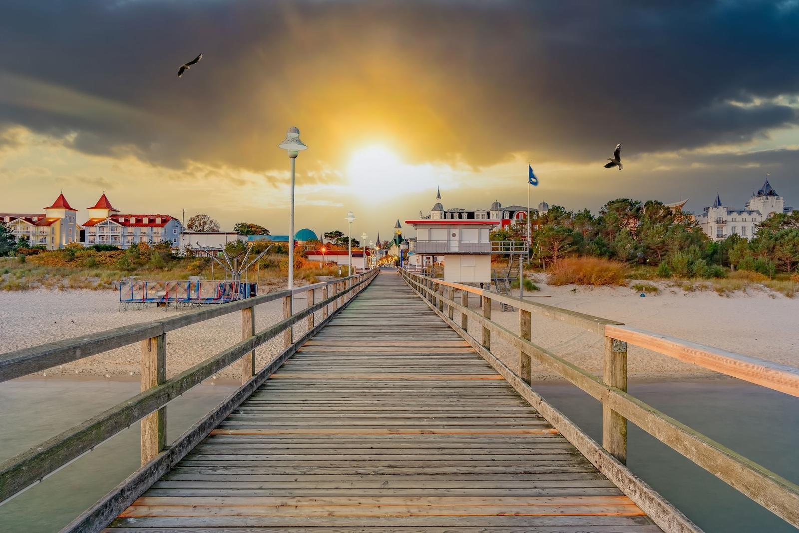 Holzbrücke führt zum Strand mit Hotels im Hintergrund.