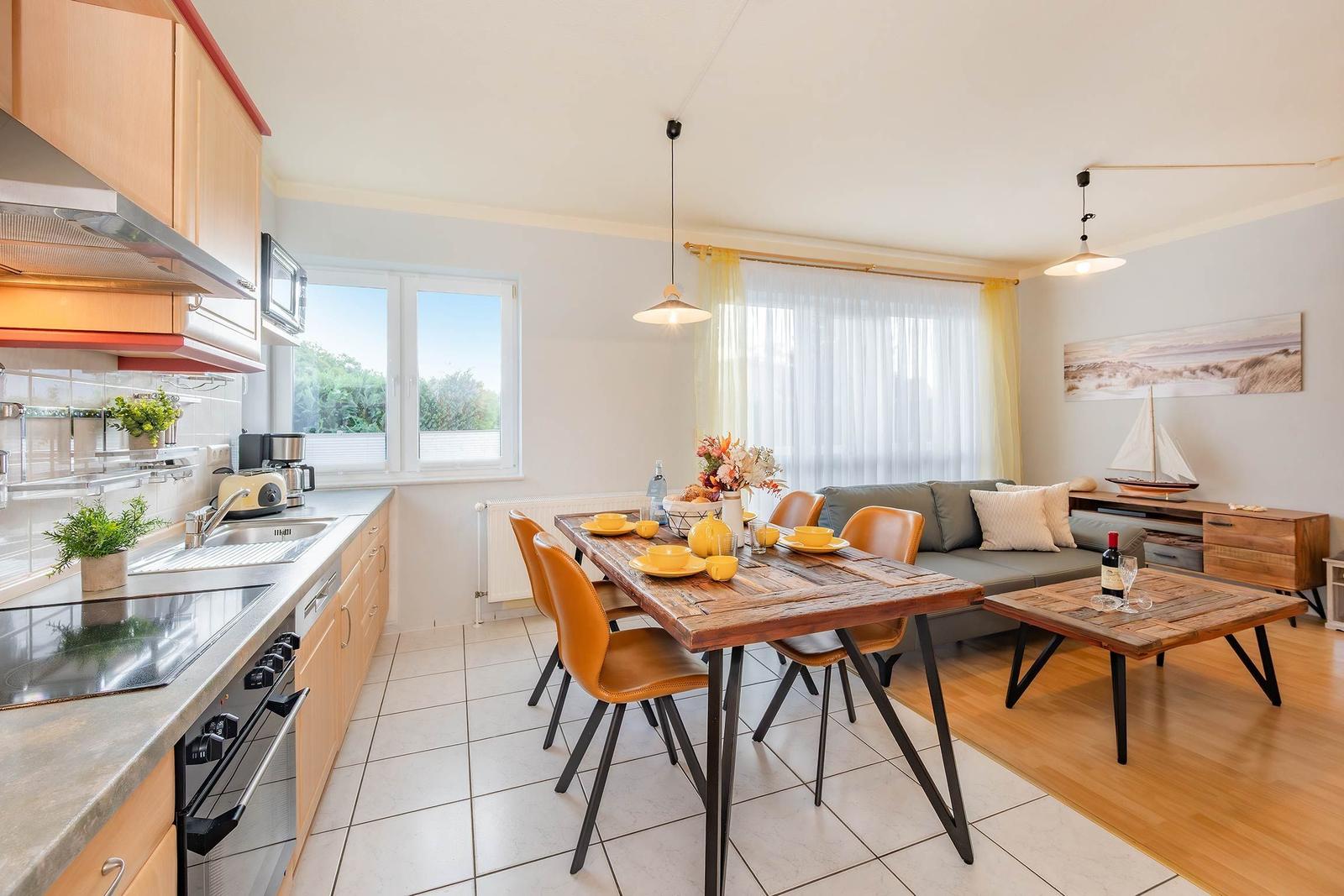 Küche mit Essbereich und Wohnzimmer mit Sofa und Holztisch.