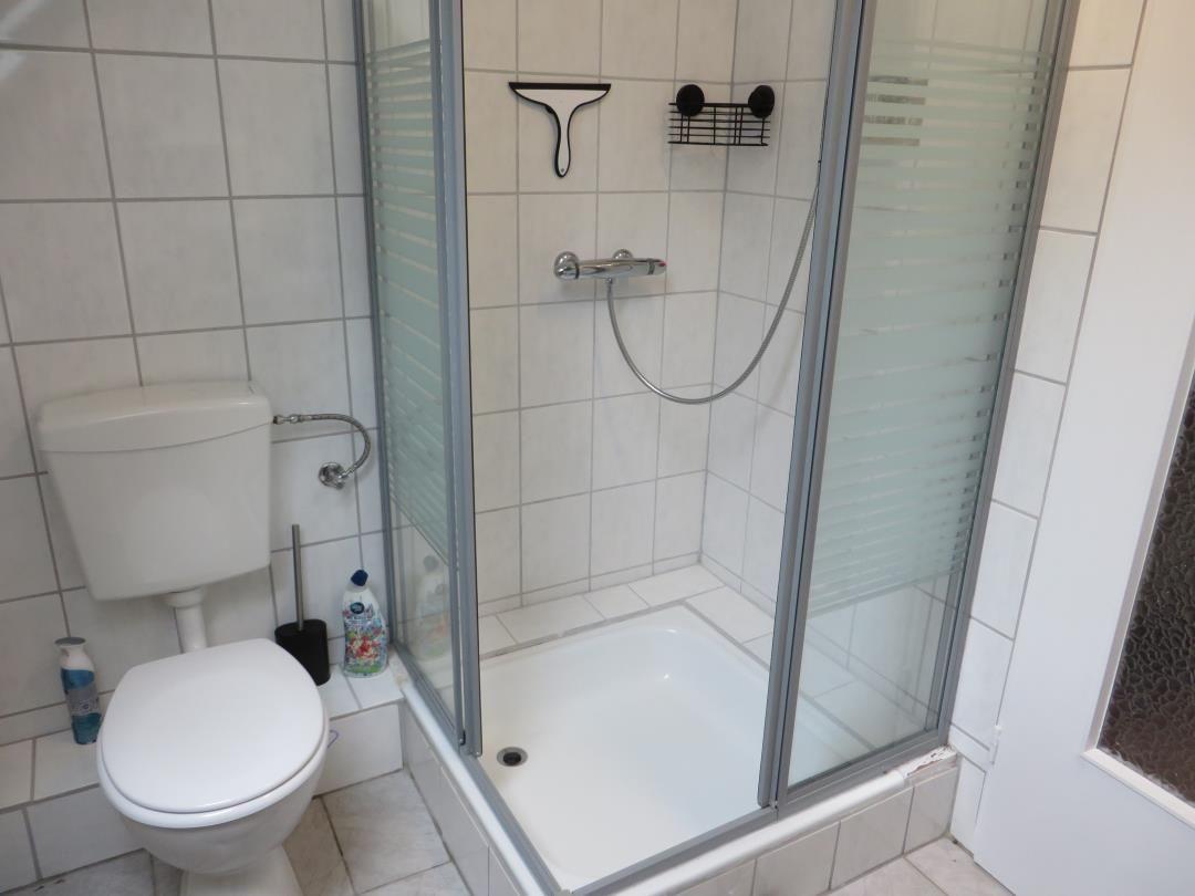 Badezimmer mit Dusche, Toilette und Fliesen