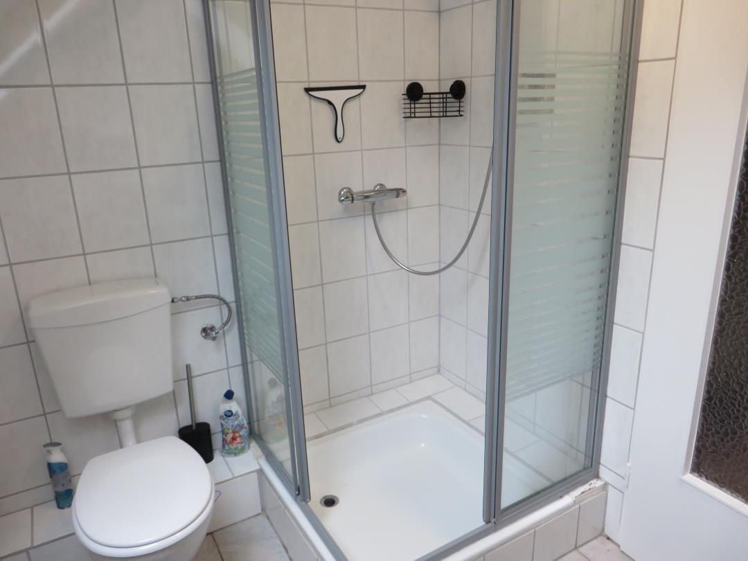 Badezimmer mit Dusche, Toilette und Fliesen