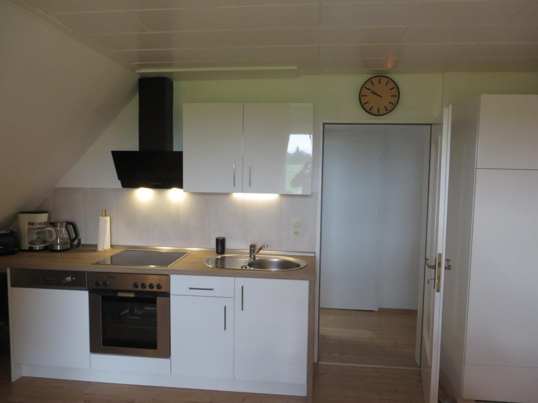 Küche mit Arbeitsplatte, Spüle, Herd und Dunstabzug.