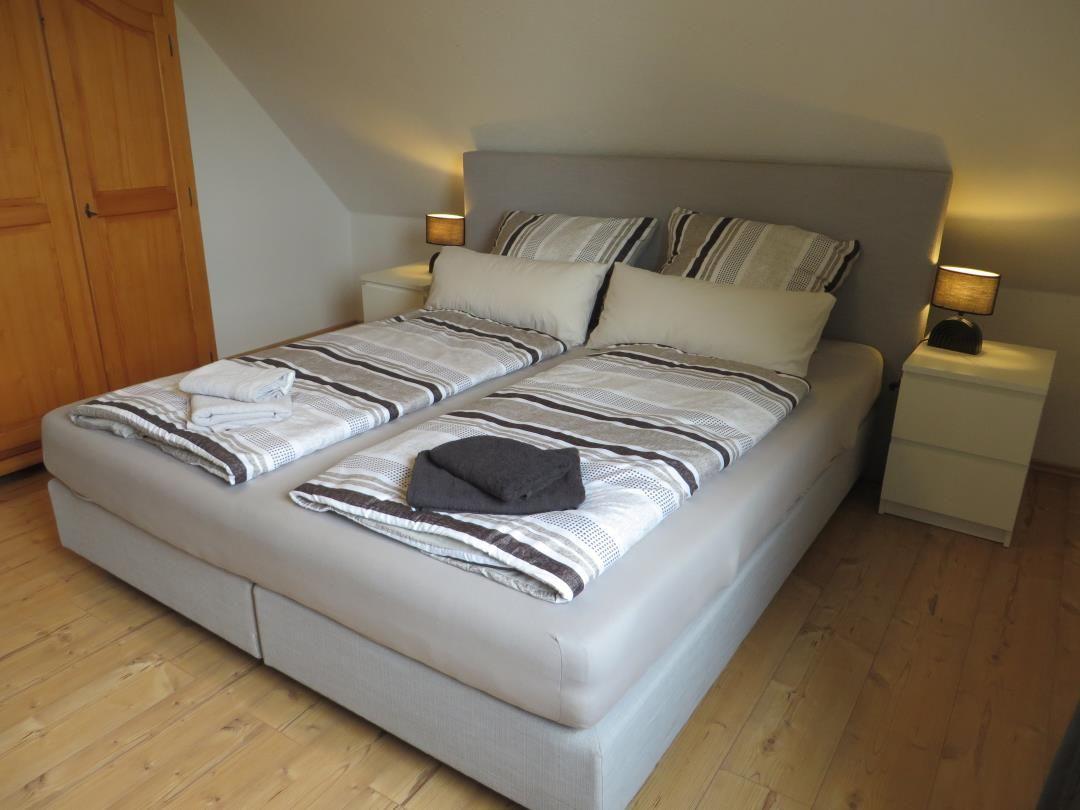 Schlafzimmer mit Doppelbett, Nachttischen und Holzboden.