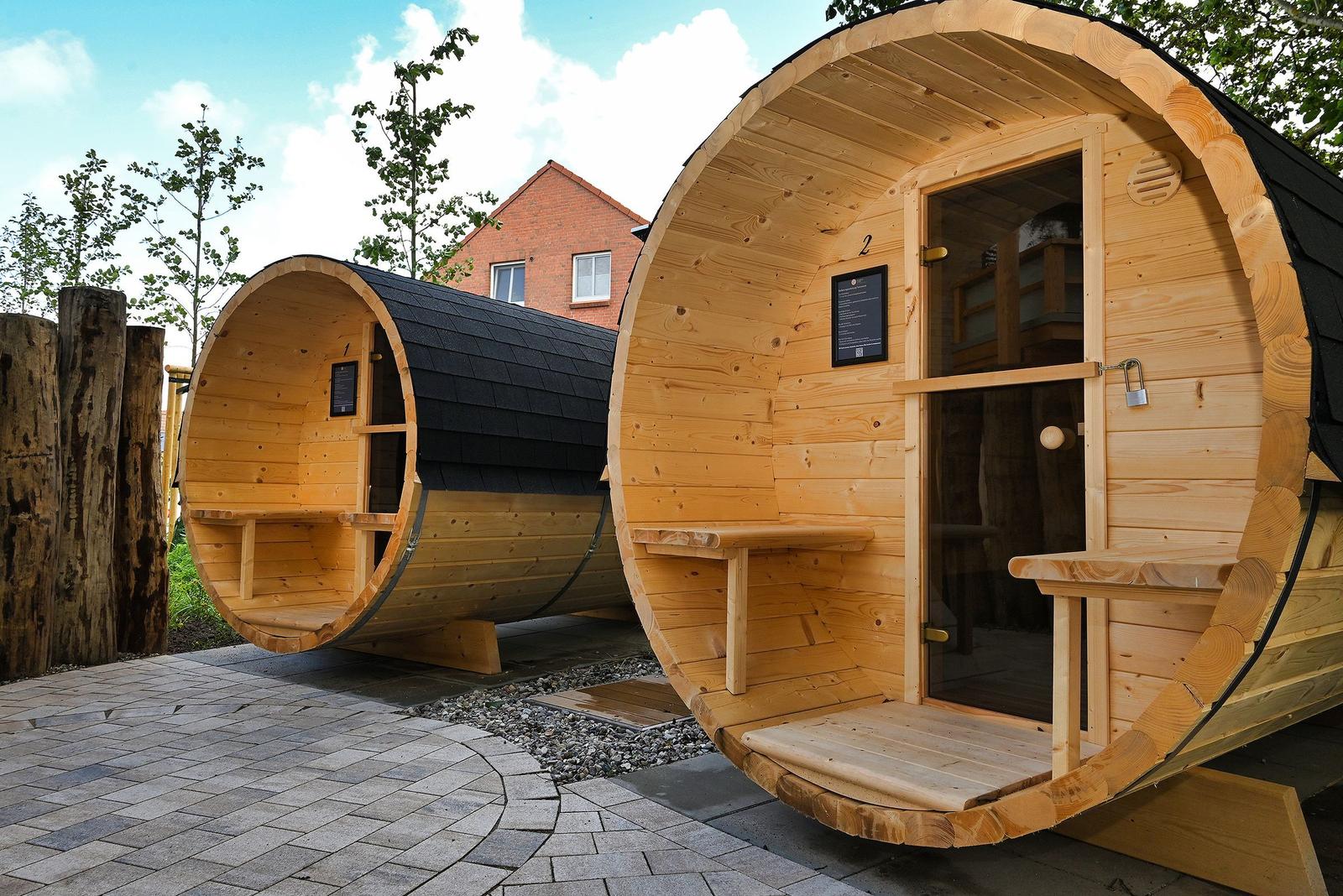 Zwei hölzerne Saunen mit Tür und Sitzbänken im Freien.