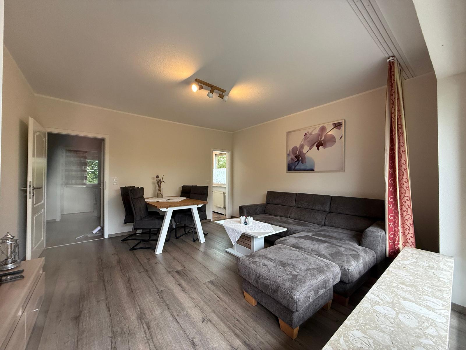 Wohnzimmer mit großer Sofaecke, Fernseher und Esstisch