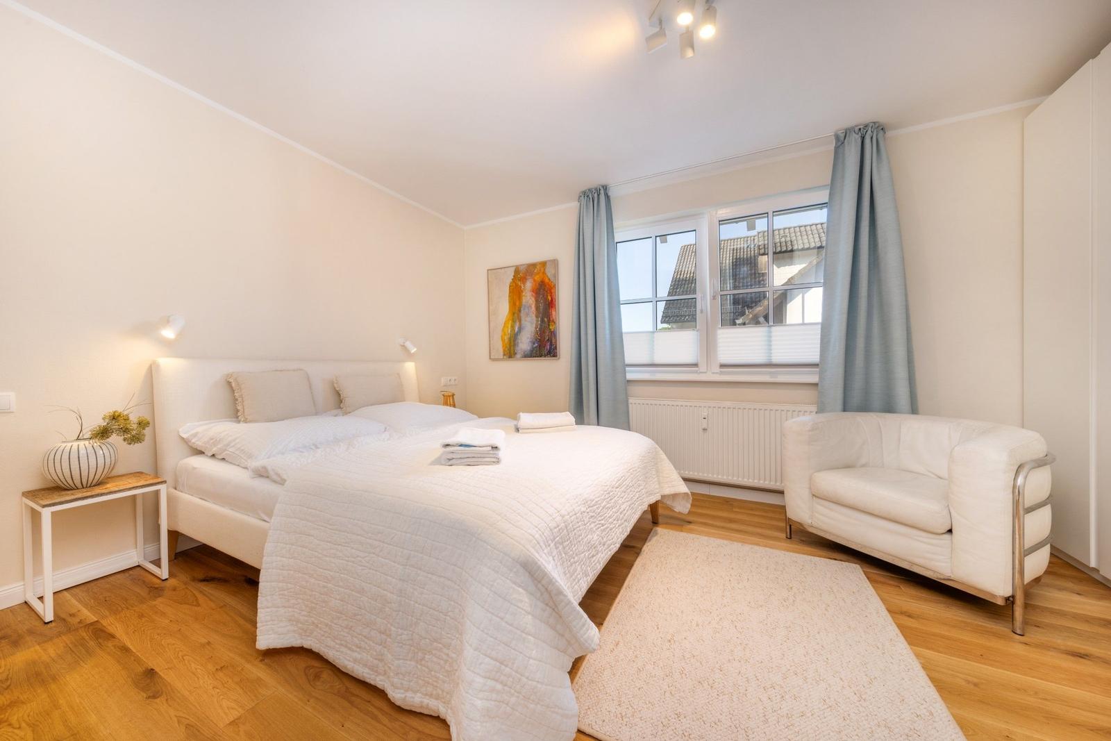 Schlafzimmer mit Bett, Sessel und Fenster mit Blick.