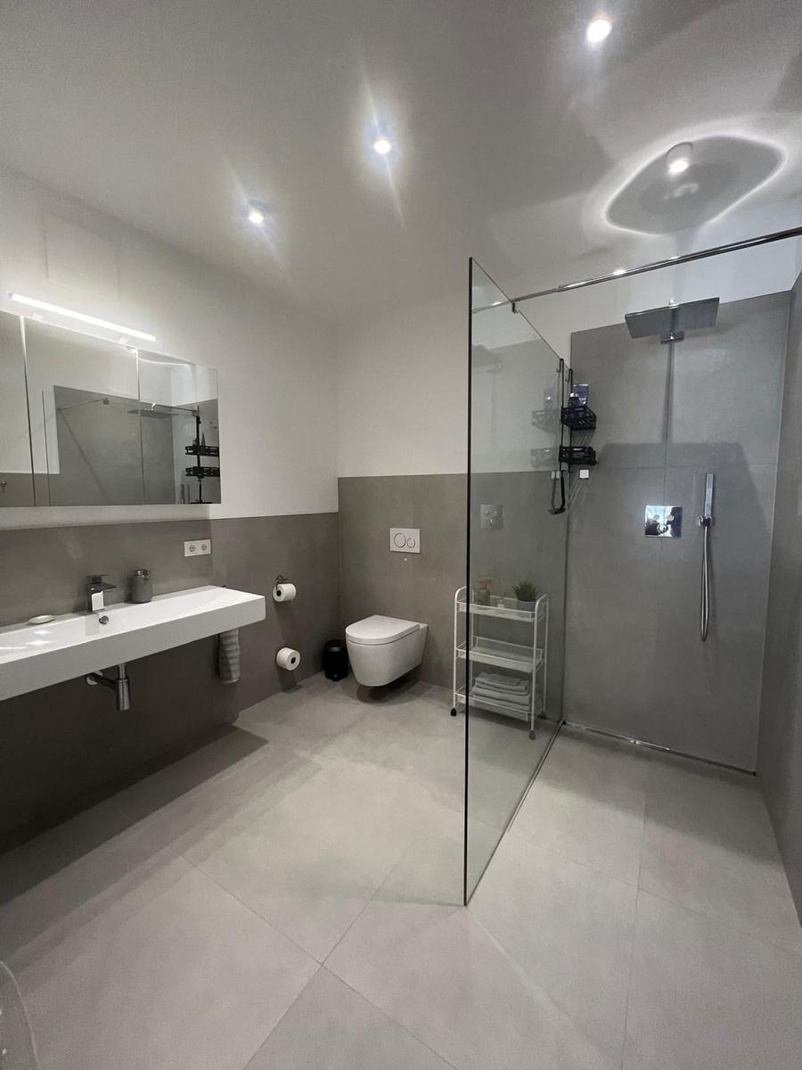 Moderne Badewanne mit Dusche, Waschbecken und Toilette.