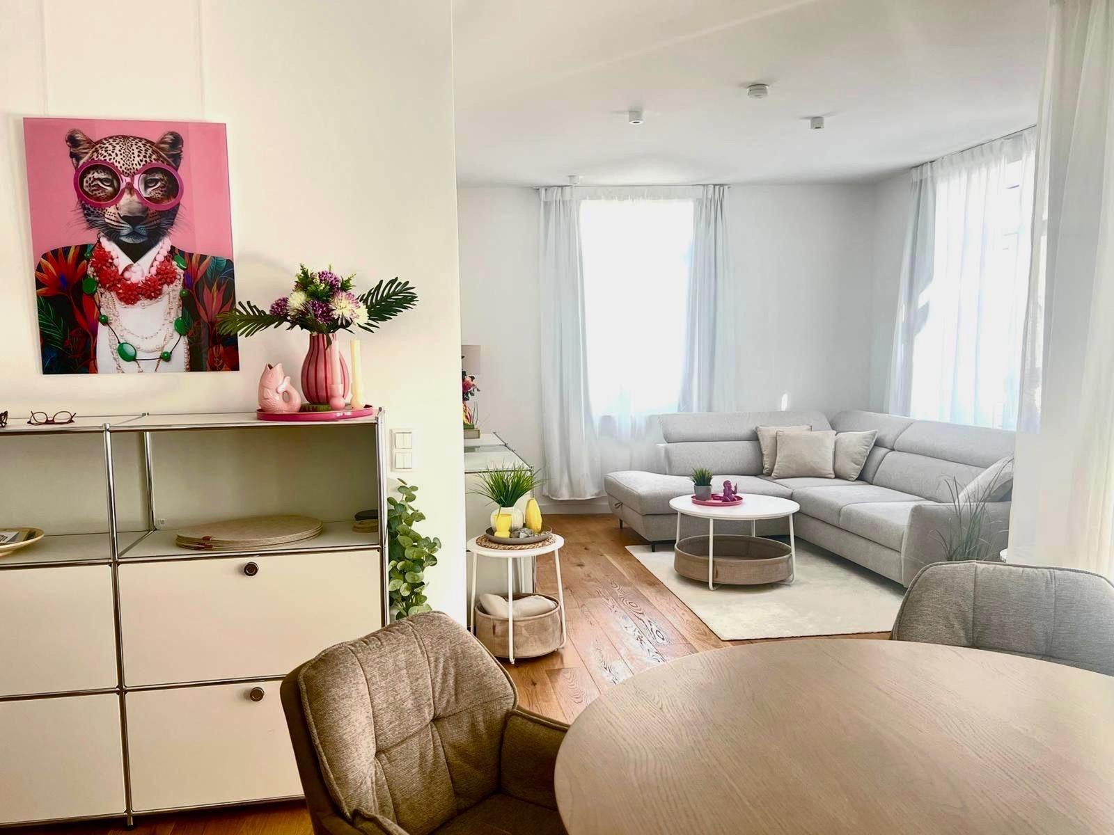 Wohnzimmer mit grauem Sofa, runden Tisch und Wandbild eines Leoparden.