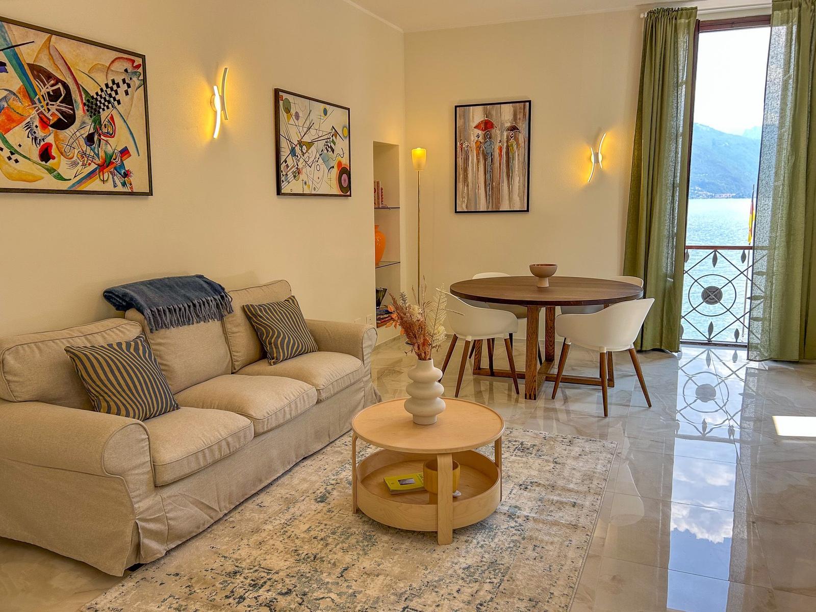 Living and dining area with sofa, table, and balcony view of water.