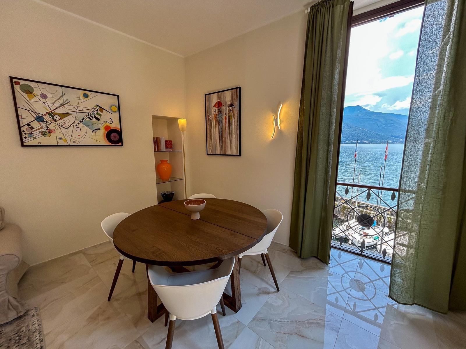 Dining room with table, chairs, and sea view from balcony.