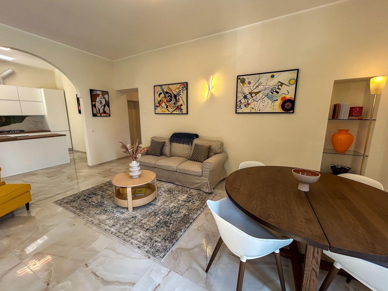 Living and dining area with sofa, dining table, and modern kitchen.