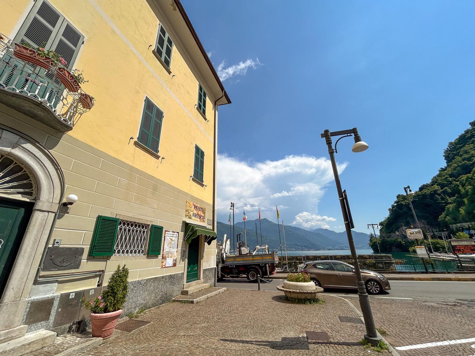 Yellow building with green shutters by a lakeside.