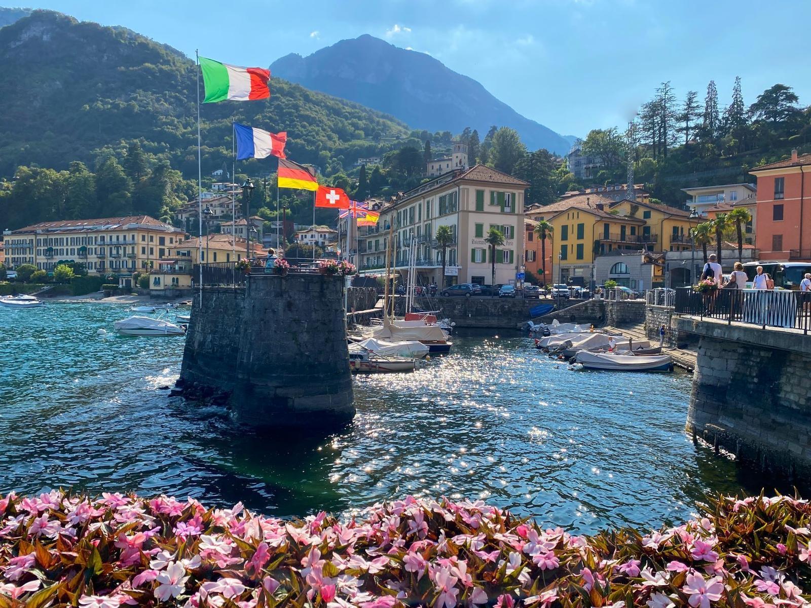 Harbor with boats, flags, and mountains in the background.
