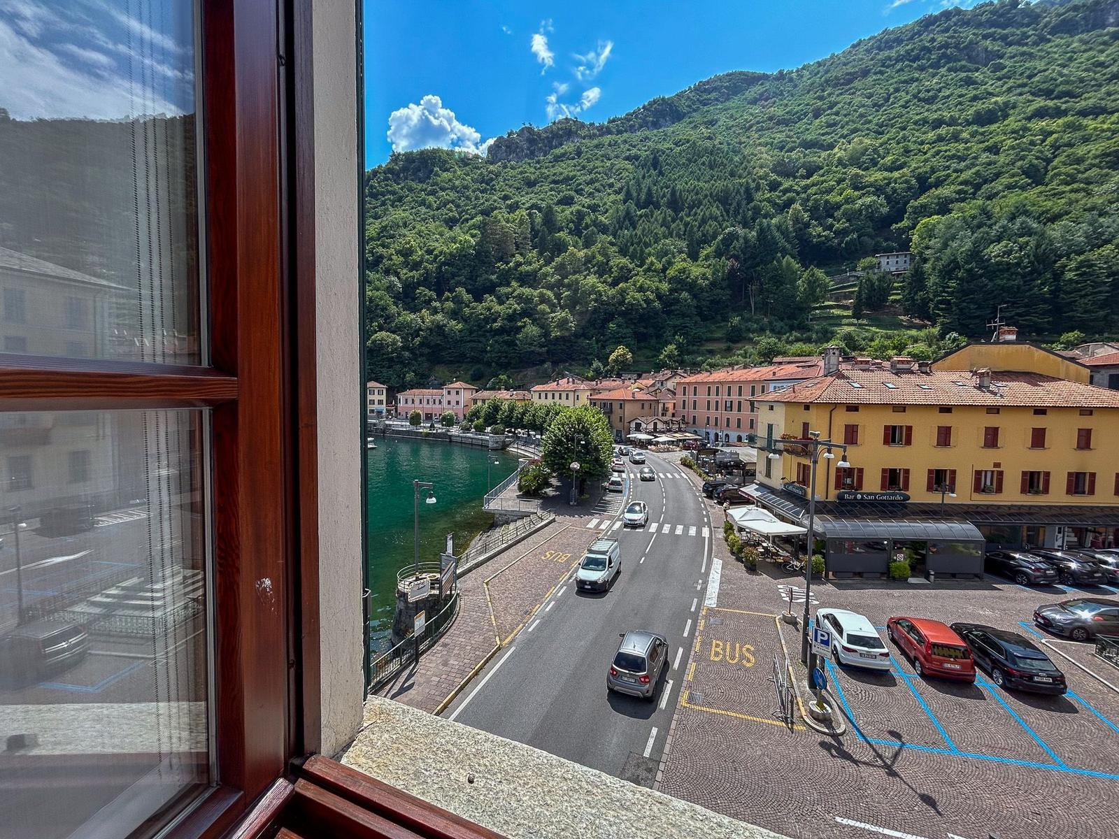 View of a lake and street with cars and green hills.