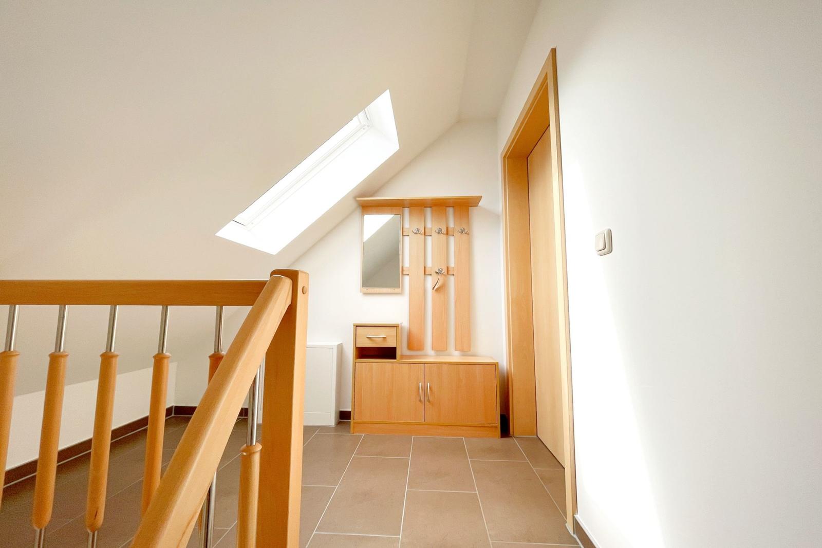 Eingangsbereich mit Holzgarderobe, Spiegel und Dachfenster.