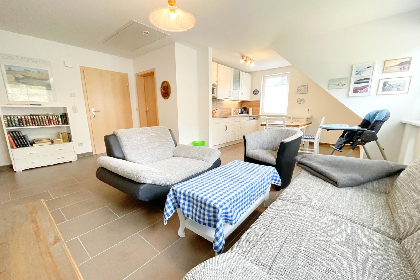 Wohn- und Essbereich mit Sofa, Sessel und Küchenbereich.