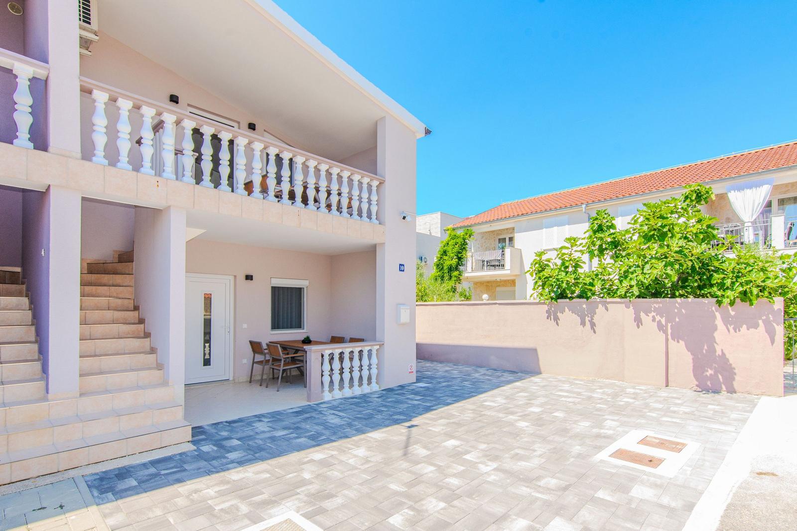 Haus mit Balkon, Terrasse und Treppe zur Eingangstür.