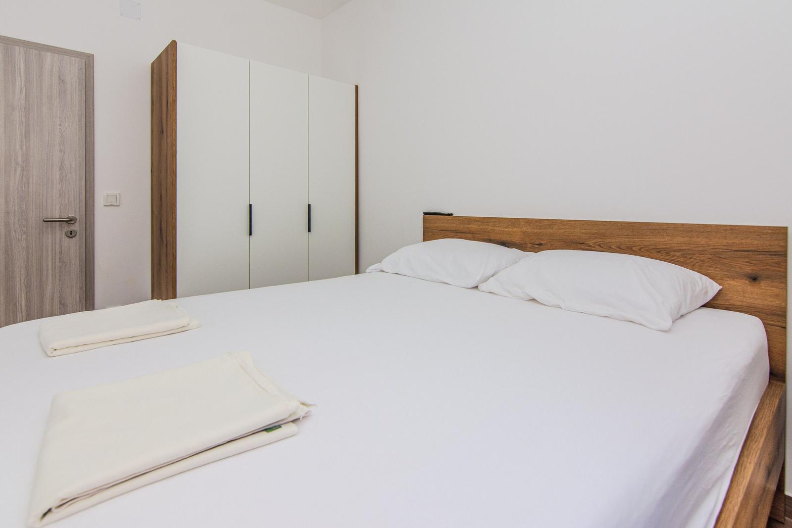 Schlafzimmer mit Doppelbett, Kleiderschrank und Tür.