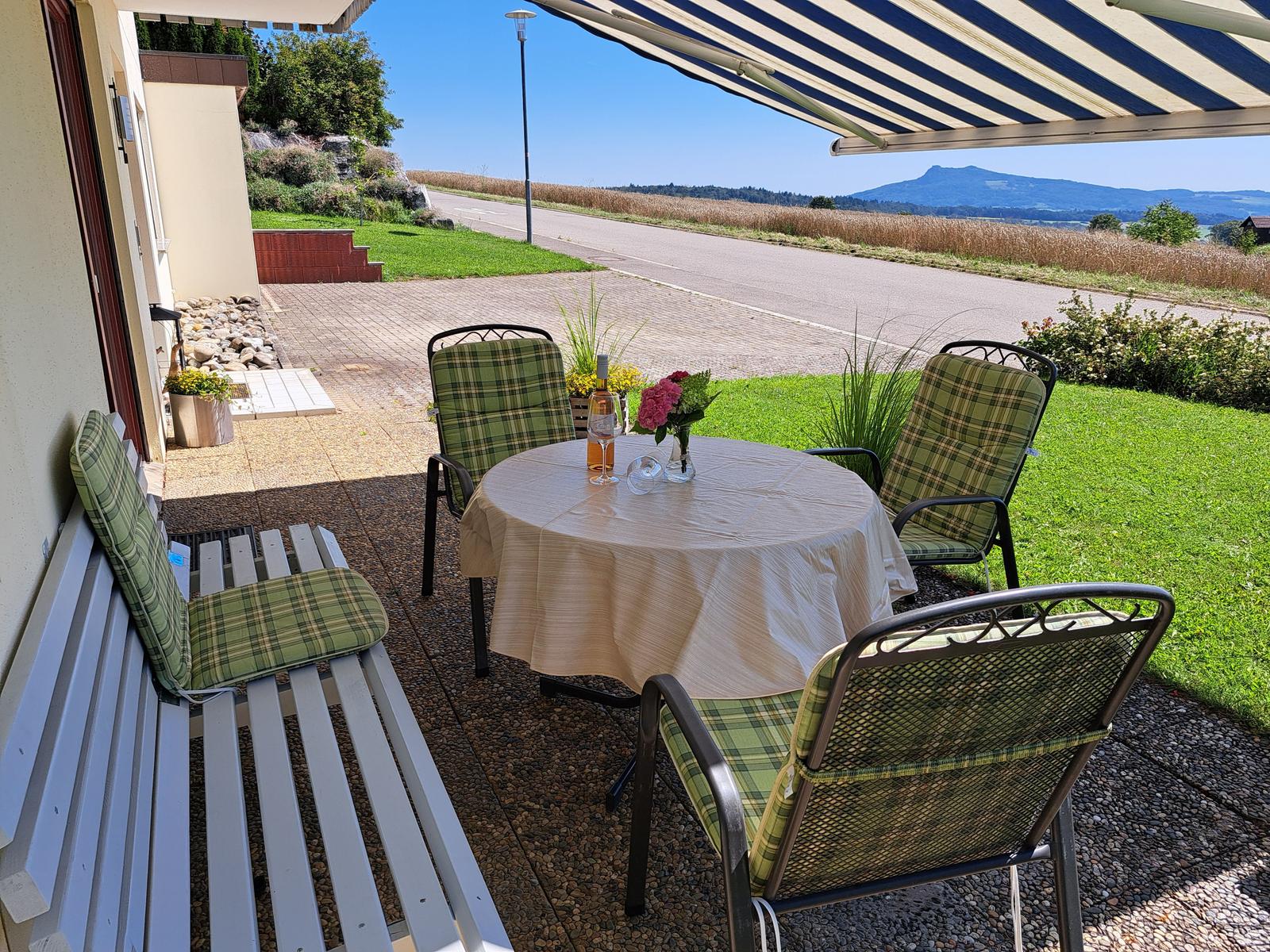 Terrasse mit Tisch, Stühlen und Blick auf die Landschaft.