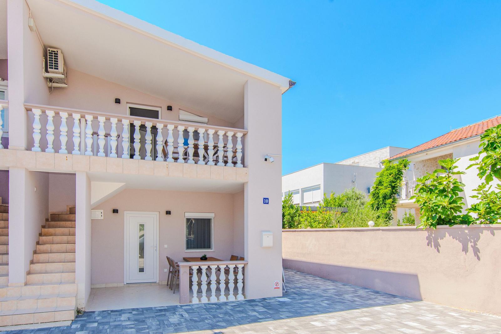 Ein zweistöckiges Haus mit Balkon, Terrasse und Außentreppe.