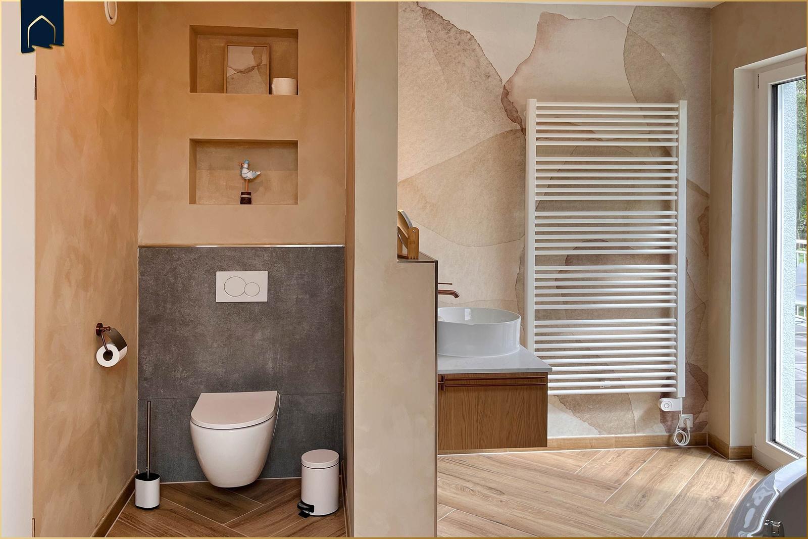 Bad mit Toilette, Waschbecken und Heizkörper. Holzdielenboden und Wandverkleidung.