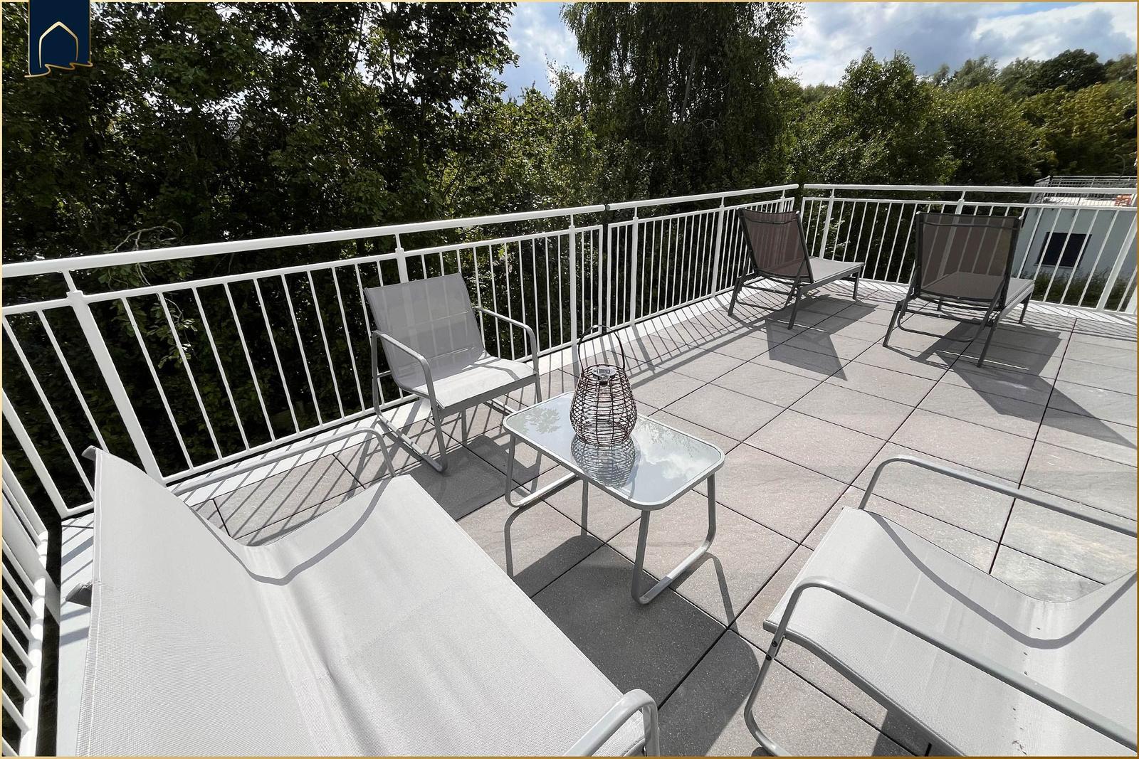 Terrasse mit Gartenmöbeln und Blick auf Bäume.