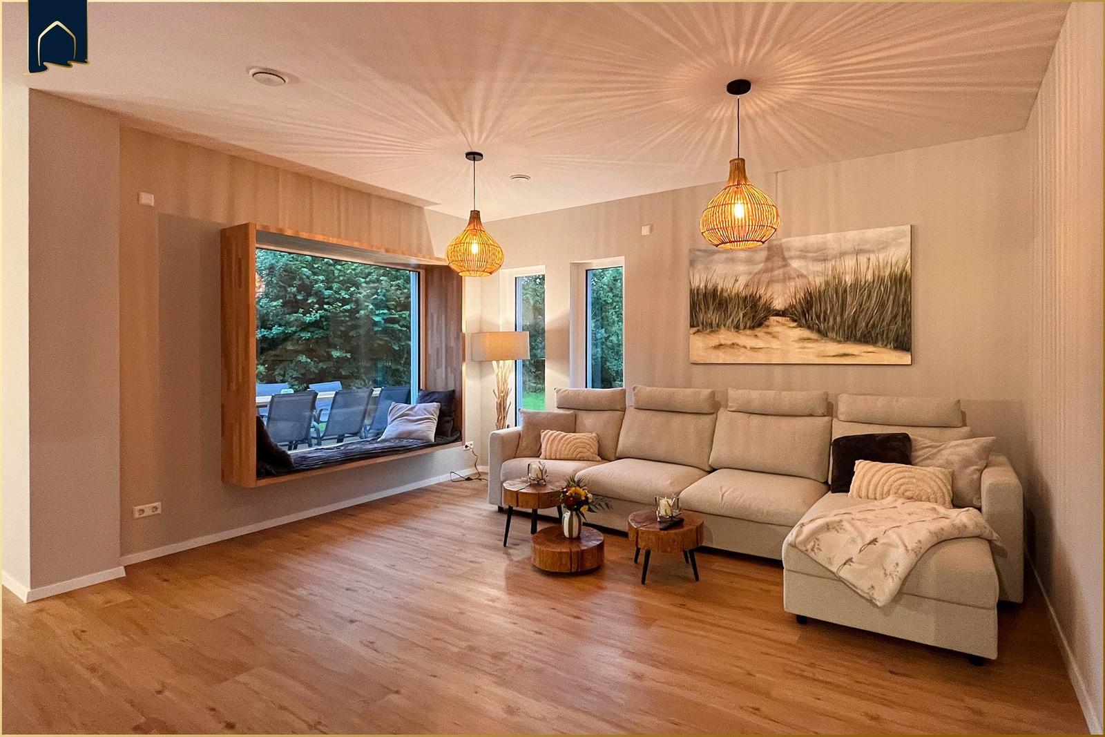 Wohnzimmer mit Sofa, Sitzbank und Holzboden. Fenster mit Blick auf Garten.