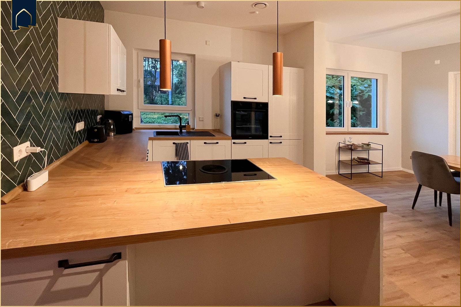 Moderne Küche mit Holzinsel und grünem Fliesenwand