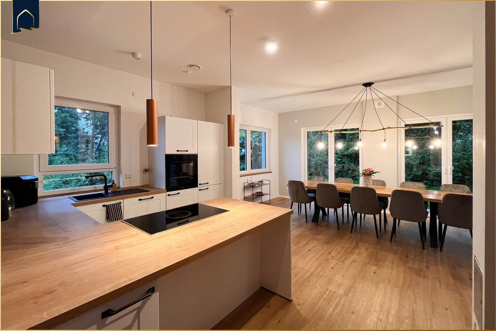 Küche mit Essbereich, Holzoberflächen und moderner Beleuchtung.