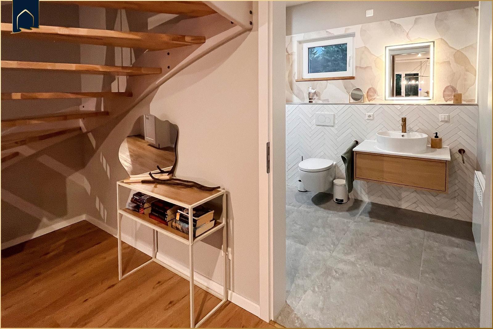 Treppenhaus mit Bücherregal und angrenzender Badewanne mit Waschbecken.