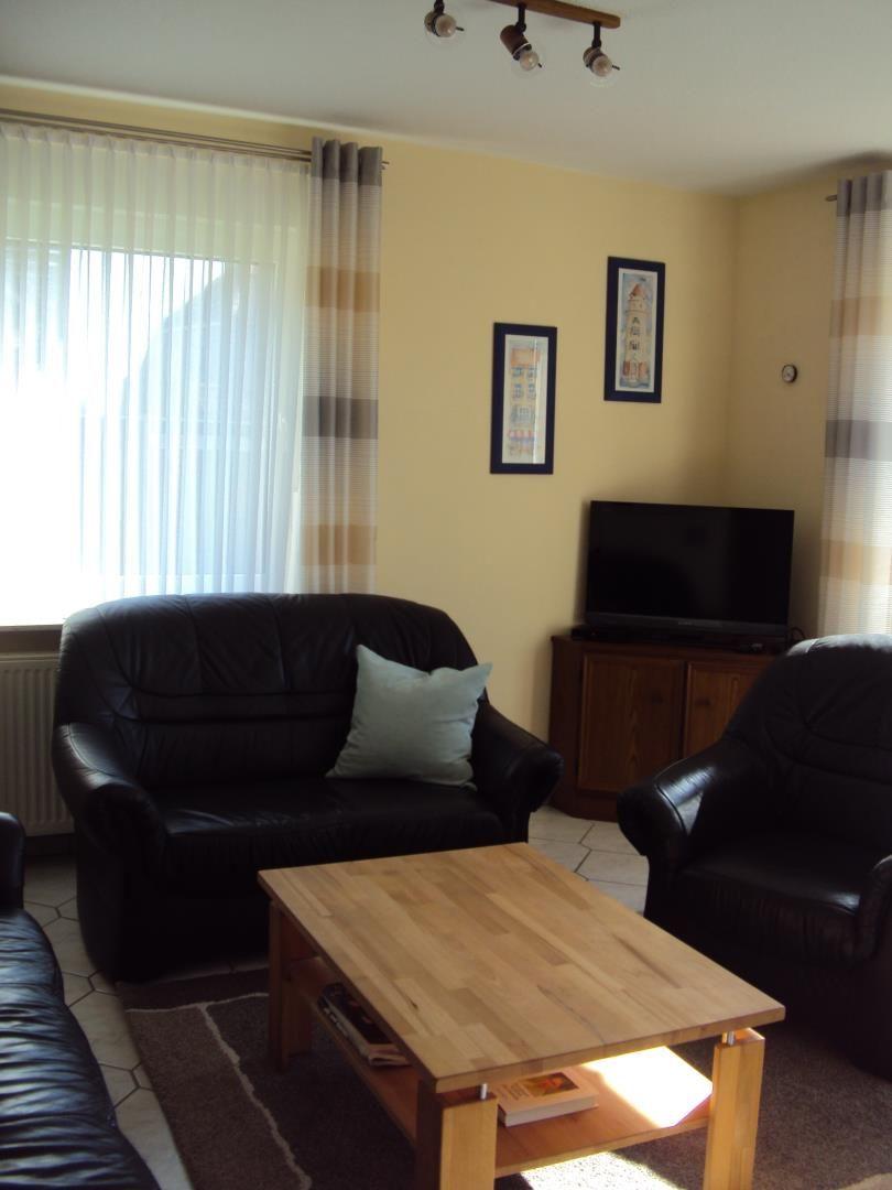 Wohnzimmer mit Ledersofa, Holztisch und Fernseher.