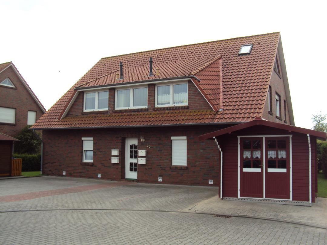 Einfamilienhaus mit rotem Dach und Backsteinfassade. Garage und Vorgarten sichtbar.