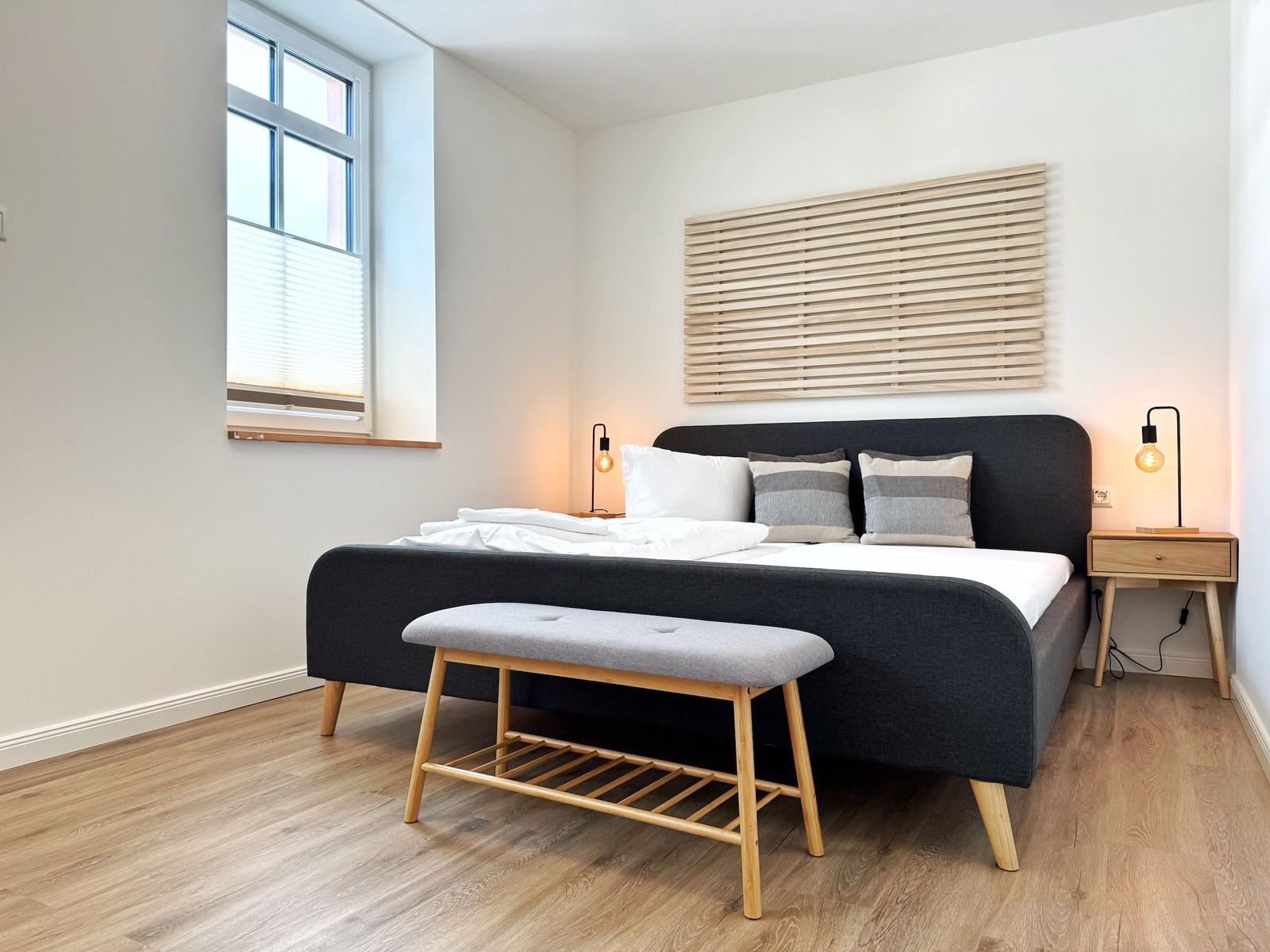 Schlafzimmer mit Bett, Nachttisch und Fenster